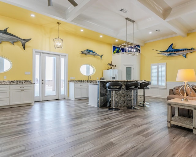 kitchen with white fridge with ice dispenser, pendant lighting, light stone countertops, light hardwood / wood-style floors, and white cabinets