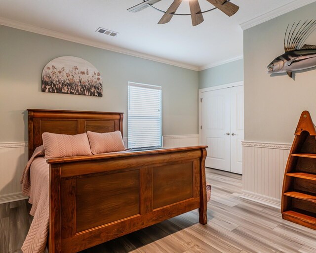 bedroom featuring crown molding, light hardwood / wood-style floors, ceiling fan, and a closet