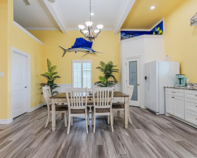 dining space with ornamental molding, an inviting chandelier, beam ceiling, and light hardwood / wood-style flooring