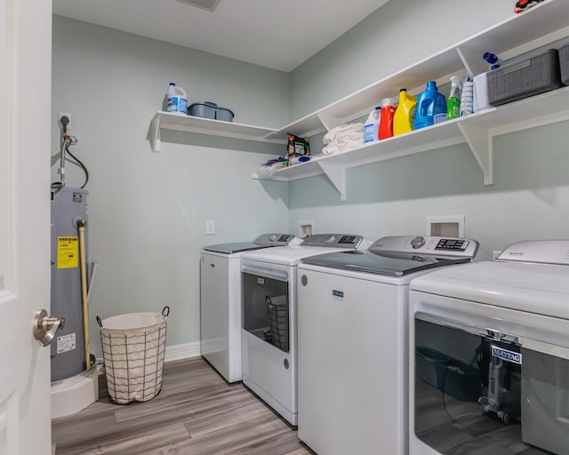 washroom with light hardwood / wood-style flooring, electric water heater, and washing machine and clothes dryer