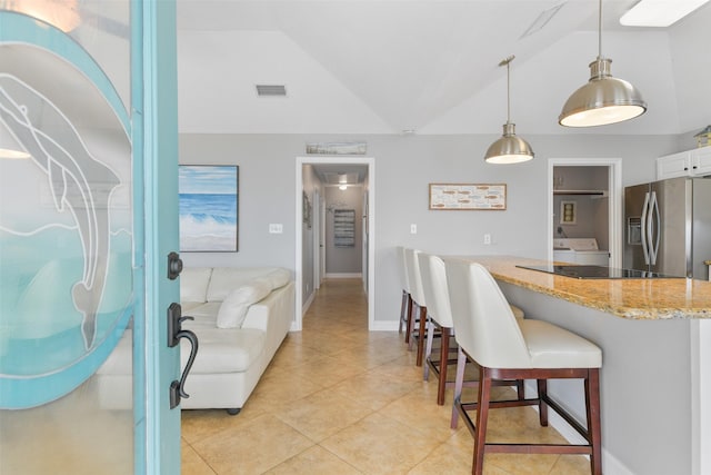 kitchen featuring vaulted ceiling, decorative light fixtures, white cabinetry, a breakfast bar area, and stainless steel refrigerator with ice dispenser