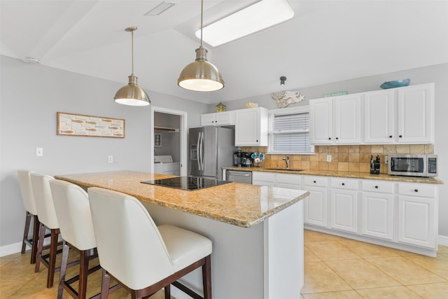 kitchen featuring appliances with stainless steel finishes, decorative light fixtures, white cabinetry, a kitchen breakfast bar, and decorative backsplash