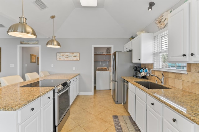 kitchen with a kitchen bar, sink, white cabinetry, appliances with stainless steel finishes, and washer / clothes dryer