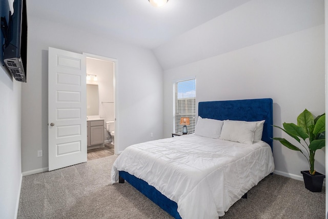 bedroom with lofted ceiling, connected bathroom, and light carpet