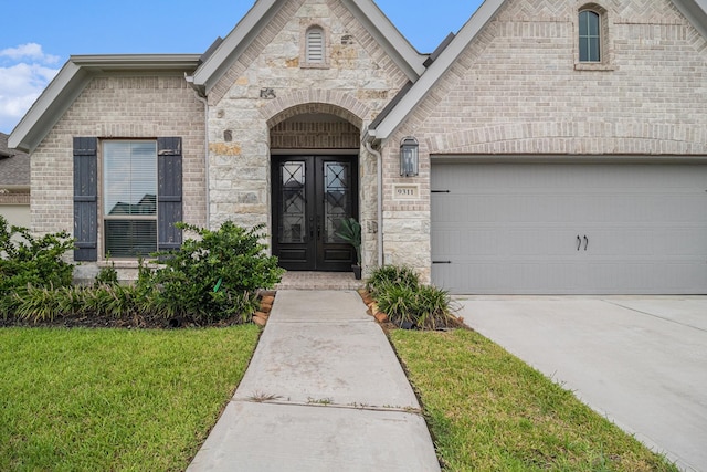 doorway to property with a garage, a lawn, and french doors