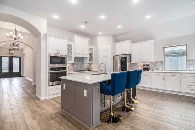 kitchen featuring stainless steel appliances, a center island with sink, and white cabinets