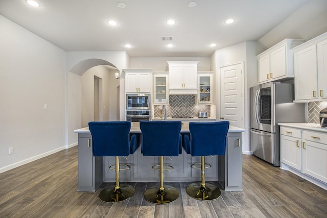 kitchen with dark hardwood / wood-style flooring, decorative backsplash, an island with sink, and white cabinets