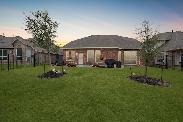 back house at dusk with a lawn