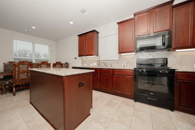 kitchen with tasteful backsplash, sink, a center island, black appliances, and light stone countertops