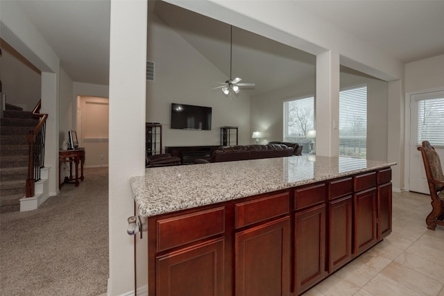 kitchen with light stone counters, light carpet, and a healthy amount of sunlight