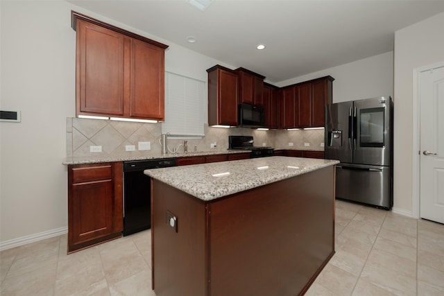 kitchen with a kitchen island, light stone counters, tasteful backsplash, black appliances, and light tile patterned flooring