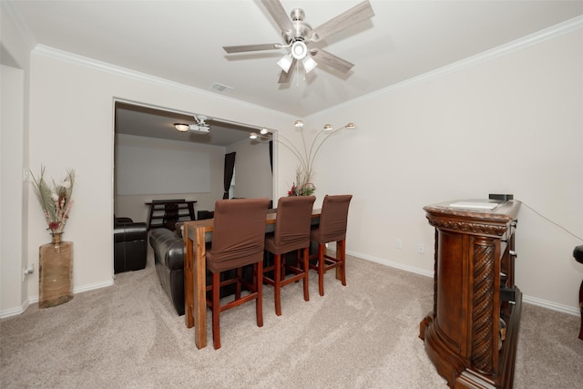 carpeted dining space featuring crown molding and ceiling fan