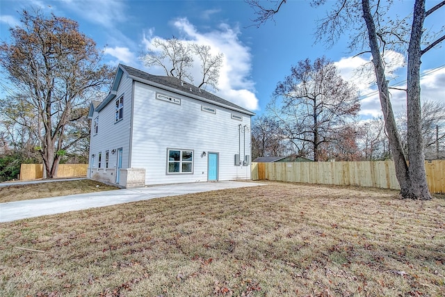 back of house featuring a garage, a lawn, and a patio