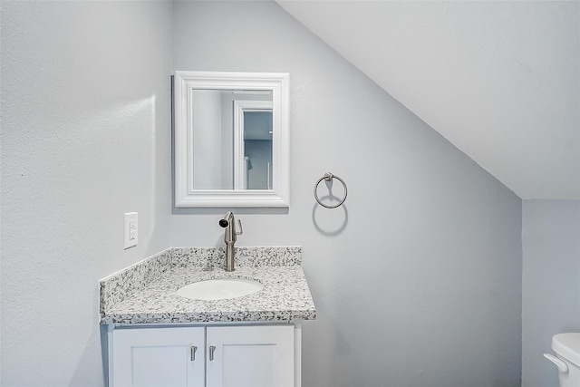 bathroom with vanity, vaulted ceiling, and toilet