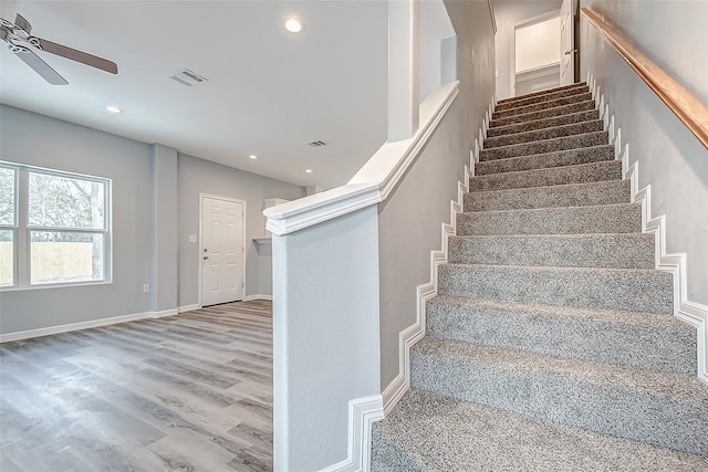 staircase with ceiling fan and hardwood / wood-style floors