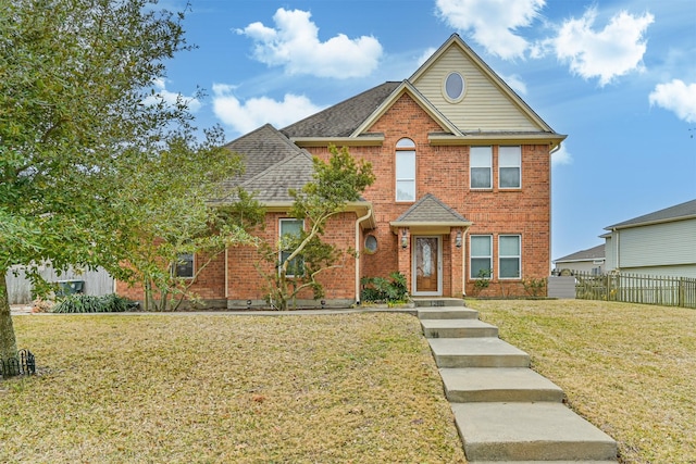 traditional-style house with brick siding, roof with shingles, a front lawn, and fence