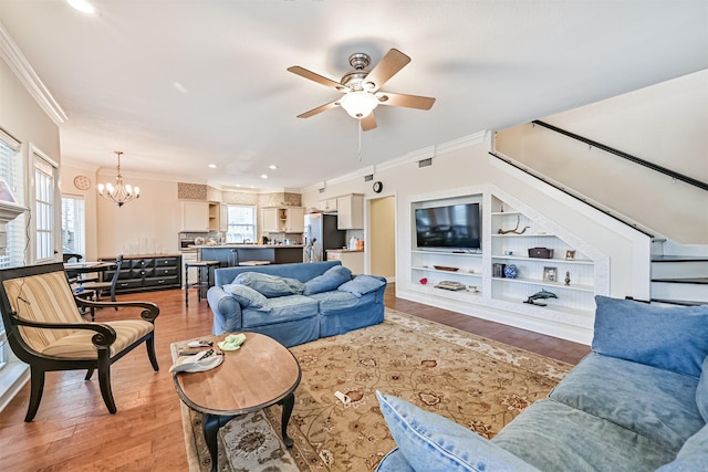 living room featuring ceiling fan with notable chandelier, crown molding, recessed lighting, and light wood-style floors