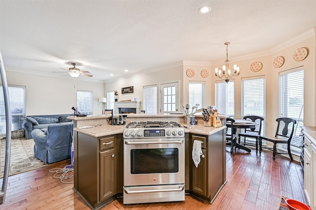 kitchen with crown molding, open floor plan, stainless steel range with gas cooktop, and light wood-type flooring