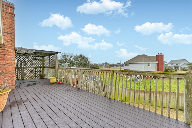 wooden deck with a residential view, a lawn, and a pergola