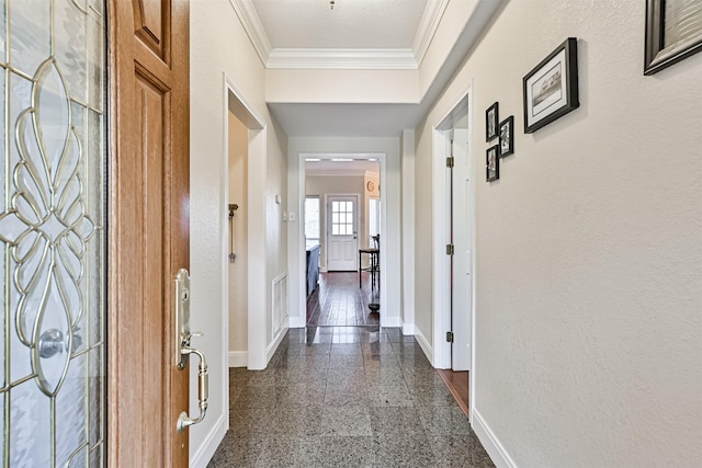 hallway with visible vents, granite finish floor, crown molding, baseboards, and a textured wall