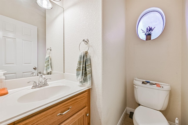 bathroom featuring vanity, toilet, and baseboards