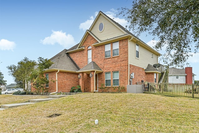 view of front of property with a front yard, stairway, fence, and brick siding