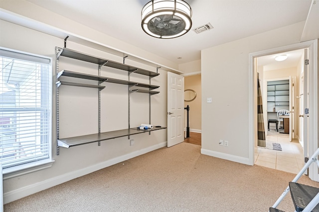 unfurnished bedroom featuring light carpet, visible vents, baseboards, and light tile patterned floors