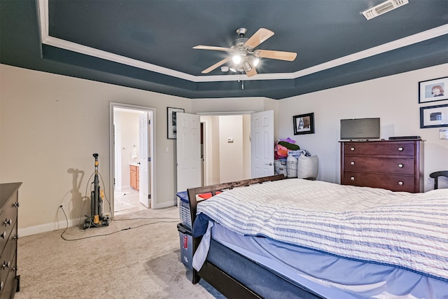 carpeted bedroom with visible vents, connected bathroom, baseboards, a tray ceiling, and a ceiling fan