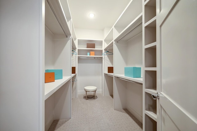 spacious closet featuring built in desk and light carpet