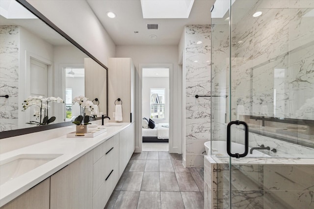 bathroom featuring shower with separate bathtub, vanity, and a skylight