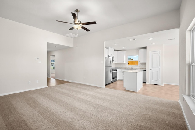 unfurnished living room featuring a wealth of natural light, light colored carpet, and ceiling fan