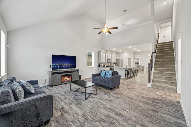 living room with ceiling fan, a fireplace, and high vaulted ceiling