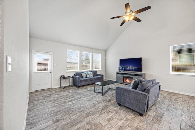 living room featuring hardwood / wood-style flooring, ceiling fan, a fireplace, and high vaulted ceiling