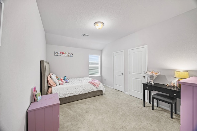 bedroom featuring lofted ceiling, carpet flooring, two closets, and a textured ceiling