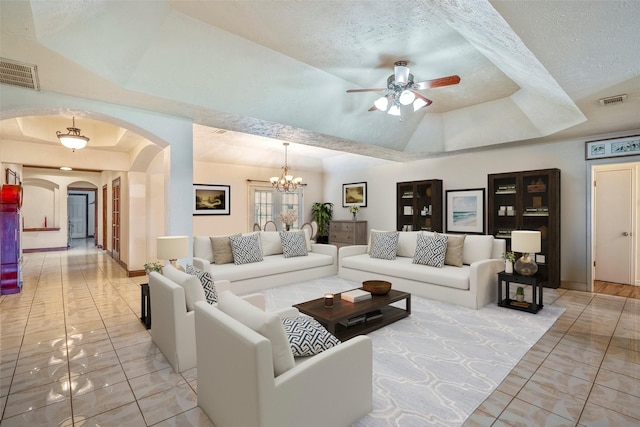 living room with a tray ceiling, ceiling fan with notable chandelier, and a textured ceiling