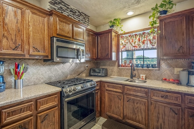 kitchen featuring stainless steel appliances, tasteful backsplash, sink, and a textured ceiling