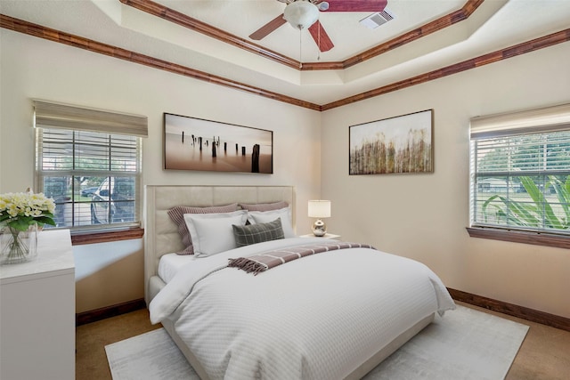 bedroom with carpet floors, ornamental molding, a raised ceiling, and ceiling fan