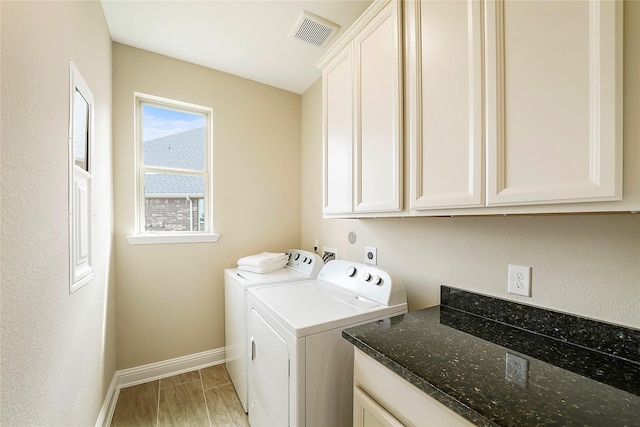 clothes washing area with independent washer and dryer, cabinets, and light hardwood / wood-style floors