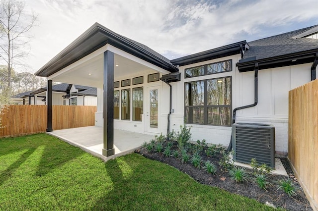 rear view of property with a patio, a yard, and central air condition unit