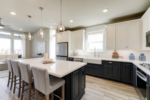 kitchen with stainless steel appliances, a kitchen island, sink, and pendant lighting