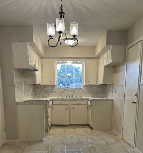 kitchen featuring hanging light fixtures, sink, backsplash, and an inviting chandelier