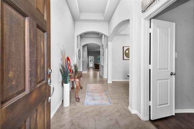 foyer with a raised ceiling and light tile patterned flooring