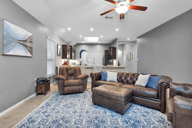 living room with vaulted ceiling with skylight and ceiling fan