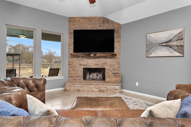 living room with ceiling fan, a stone fireplace, and vaulted ceiling