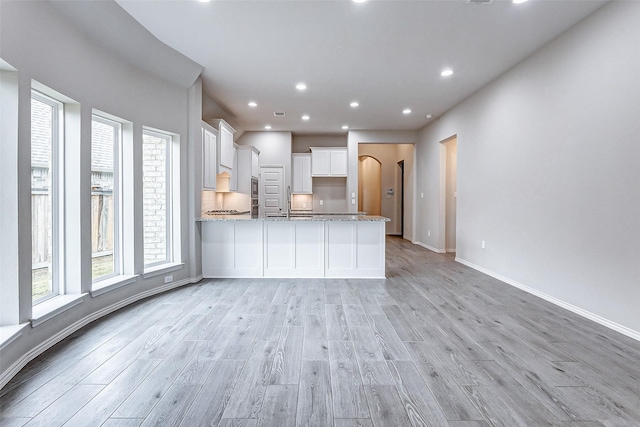 kitchen featuring white cabinetry, sink, light hardwood / wood-style flooring, and light stone countertops