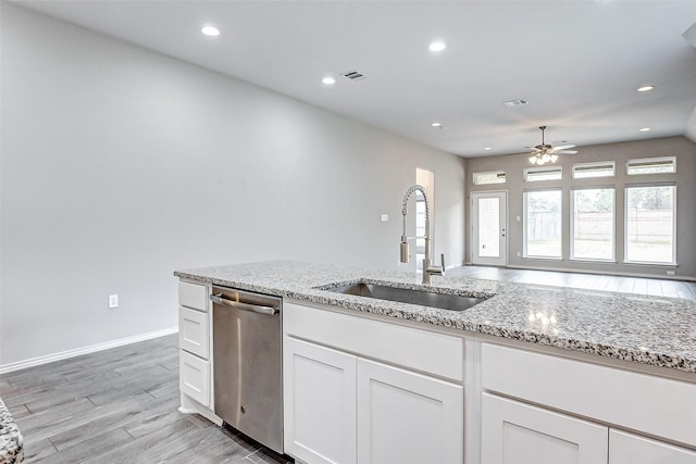 kitchen featuring sink, light stone counters, stainless steel dishwasher, light hardwood / wood-style floors, and white cabinets