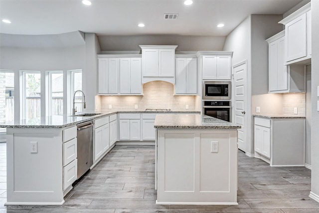 19723 Sandstone Bluff Way, Cypress, TX 77433 - kitchen with stainless steel appliances, a kitchen island, a sink, visible vents, and a peninsula