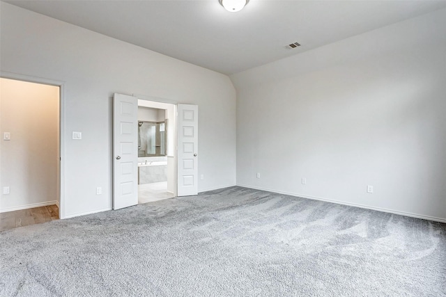 unfurnished bedroom featuring vaulted ceiling, carpet, and ensuite bath