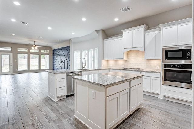 kitchen featuring sink, appliances with stainless steel finishes, a center island, tasteful backsplash, and kitchen peninsula