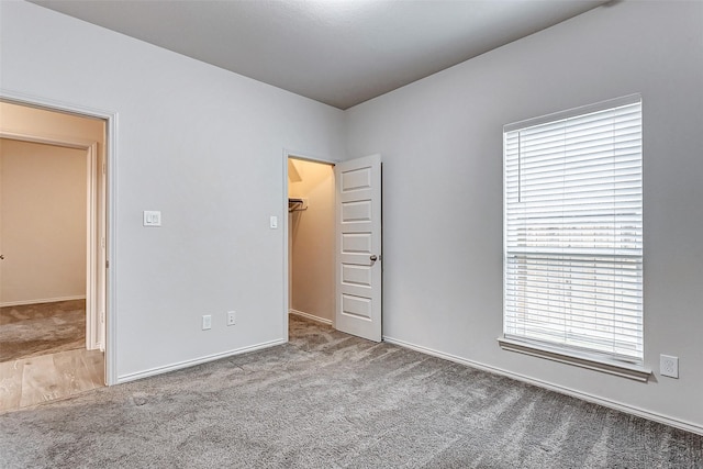 unfurnished bedroom with a spacious closet, carpet floors, and a closet